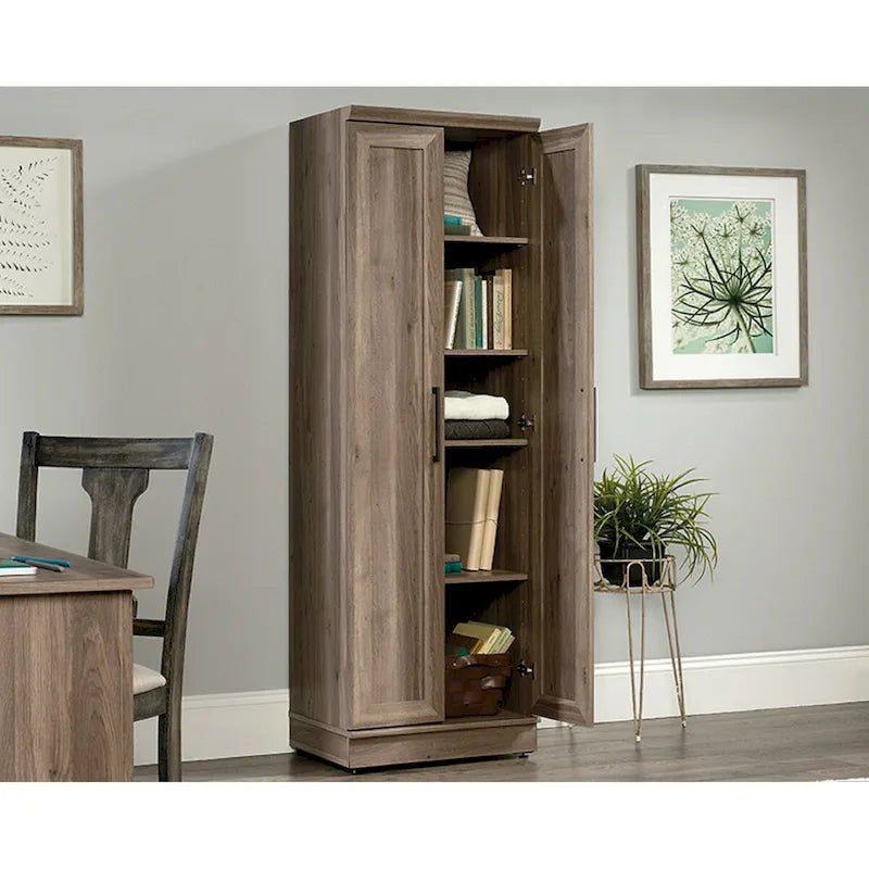 Armoire de rangement au fini chêne décapé, dotée de portes à panneaux et d'étagères réglables.